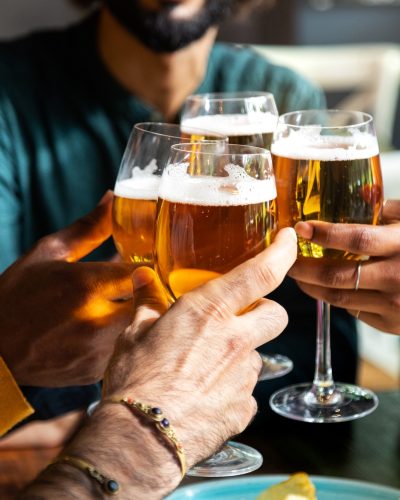 close-up-of-friends-toasting-with-beer-indoors-friends-having-fun-at-bar-cheering-with-beer-.jpg